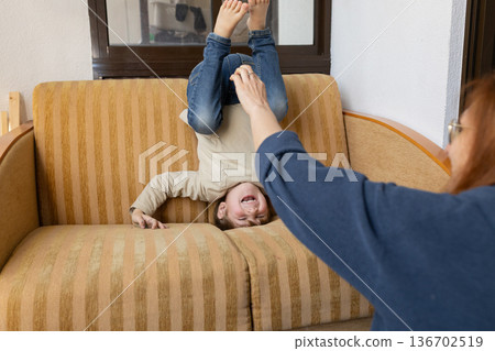 Happy child laughing playing upside down on couch Happy child laughing playing upside down on couch 136702519