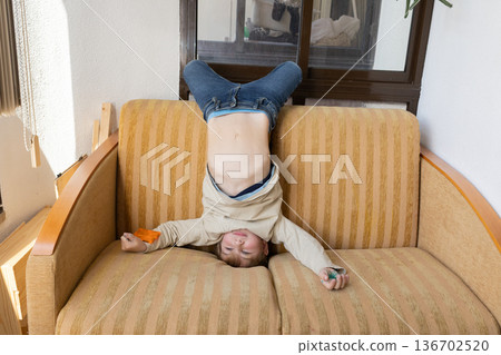 Young boy playing upside down on a comfortable sofa 136702520
