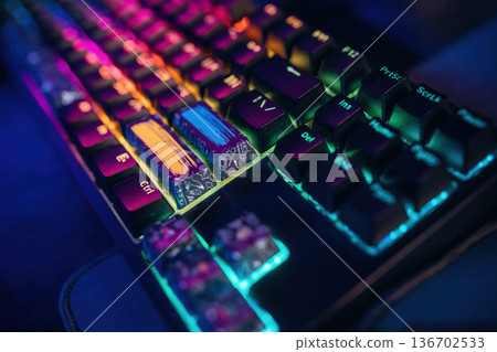 Colorful keyboard. Gaming computer is in the dark room with neon lighting Colorful keyboard. Gaming computer is in the dark room with neon lighting 136702533