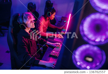 In headphones. Gamers are playing video game by computers In headphones. Gamers are playing video game by computers 136702557