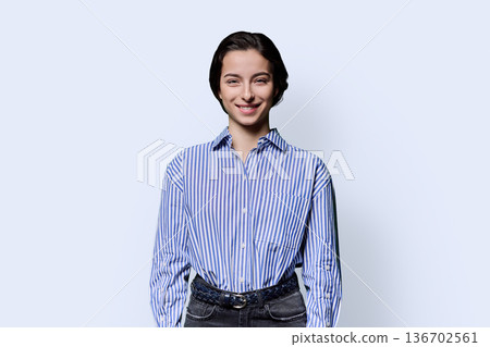 Portrait of smiling young beautiful girl looking at camera on white background 136702561