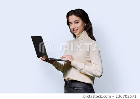 Portrait of smiling teenage girl holding laptop on white studio background Portrait of smiling teenage girl holding laptop on white studio background 136702571