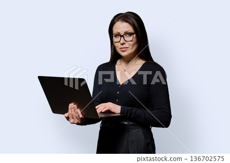 Portrait of mature woman with laptop on white studio background Portrait of mature woman with laptop on white studio background 136702575