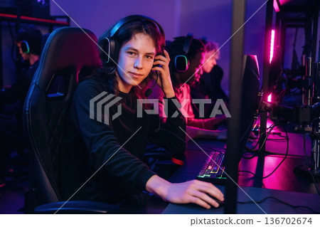 Dude with long hair is sitting. Gamers are playing video game by computers Dude with long hair is sitting. Gamers are playing video game by computers 136702674
