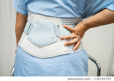 Asian senior pain back wearing elastic support belt with walker. 136702705
