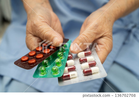 Asian elderly woman holding pill drug in hand, strong healthy medical. Asian elderly woman holding pill drug in hand, strong healthy medical. 136702708