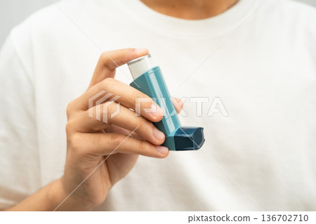 Asthma and chronic obstructive pulmonary disease COPD, Asian young man using metered dose inhaler MDI. Asthma and chronic obstructive pulmonary disease COPD, Asian young man using metered dose inhaler MDI. 136702710