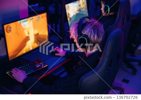 Sitting and focused. Gamers are playing video game by computers Sitting and focused. Gamers are playing video game by computers 136702726