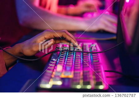 Close up view of keyboard and hands. Gamers are playing video game by computers Close up view of keyboard and hands. Gamers are playing video game by computers 136702787