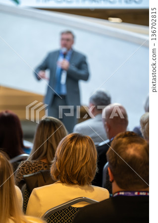Professional conference presentation with speaker addressing audience during business event and networking 136702815