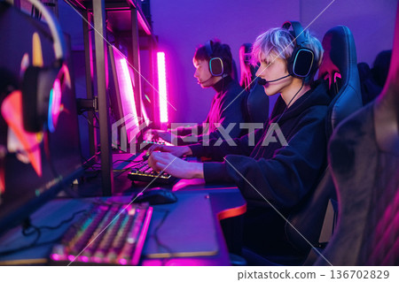 Side view. Gamers are playing video game by computers Side view. Gamers are playing video game by computers 136702829