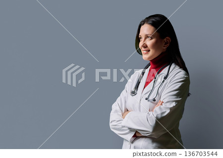 Profile view of positive female doctor with stethoscope on gray background Profile view of positive female doctor with stethoscope on gray background 136703544