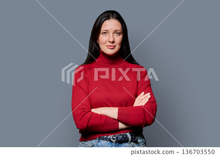 Portrait of beautiful smiling 40 years old woman posing on grey background Portrait of beautiful smiling 40 years old woman posing on grey background 136703550