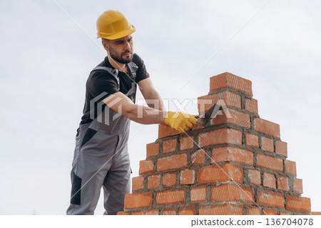 Bunch of bricks. Construction worker is at job outdoors 136704078