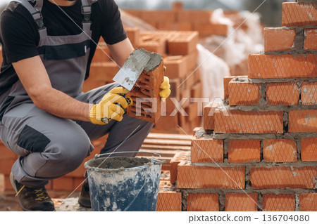 Building the wall. Close up view of construction man that is working with bricks Building the wall. Close up view of construction man that is working with bricks 136704080