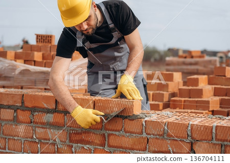 Busy by working with bricks. Construction worker is at job outdoors Busy by working with bricks. Construction worker is at job outdoors 136704111