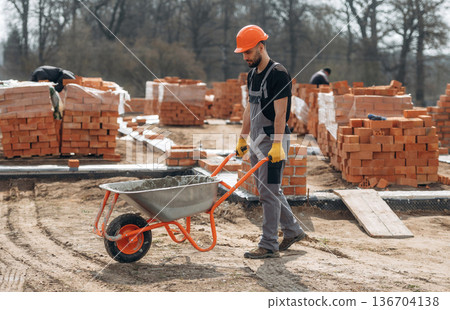 Construction worker is at job with bricks outdoors Construction worker is at job with bricks outdoors 136704138