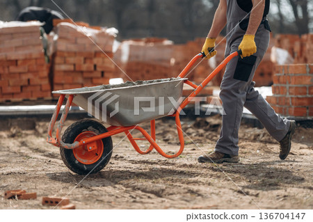 Transporting concrete. Close up view of construction man that is working with bricks Transporting concrete. Close up view of construction man that is working with bricks 136704147