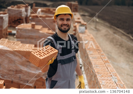 Showing the brick. Construction worker is at job with outdoors Showing the brick. Construction worker is at job with outdoors 136704148