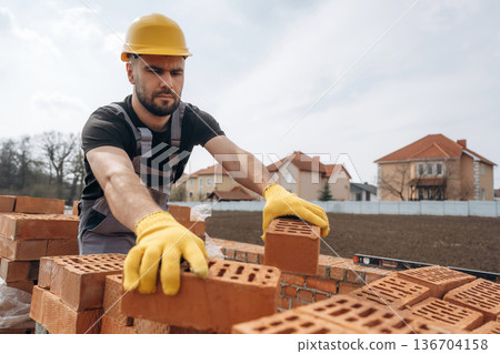 Work in progress. Construction man is at job with bricks outdoors 136704158