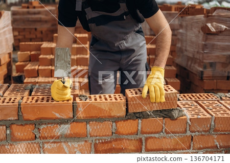 Creating the wall. Close up view of construction man that is working with bricks Creating the wall. Close up view of construction man that is working with bricks 136704171