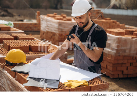 Project plan on the paper. Construction worker is at job with bricks outdoors 136704205