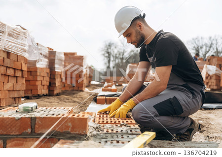 Construction worker is at job with bricks outdoors Construction worker is at job with bricks outdoors 136704219