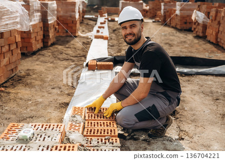 Construction worker is at job with bricks outdoors 136704221