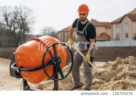 Man is working on the construction site with concrete mixer Man is working on the construction site with concrete mixer 136704230