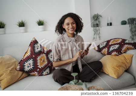 Relaxed Woman Teaching With Smartphone In Cozy Setting Surrounded By Greenery And Soft Cushions Relaxed Woman Teaching With Smartphone In Cozy Setting Surrounded By Greenery And Soft Cushions 136704239