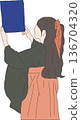 A woman in a hakama holding up her diploma 136704320