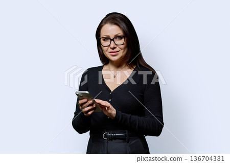 Portrait mature woman with smartphone on white studio background Portrait mature woman with smartphone on white studio background 136704381