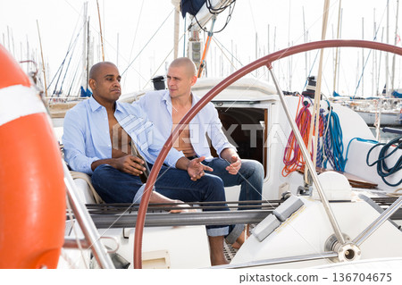 Two men in blue shirts sitting on sailing yacht in the port 136704675