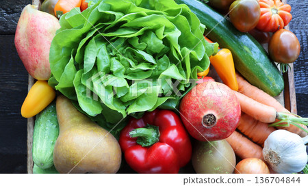 Organic vegetables from the garden - carrots, tomatoes, peppers, cucumbers, lettuce and fruits in wooden box . Raw healthy food concept. Top view Organic vegetables from the garden - carrots, tomatoes, peppers, cucumbers, lettuce and fruits in wooden box . Raw healthy food concept. Top view 136704844