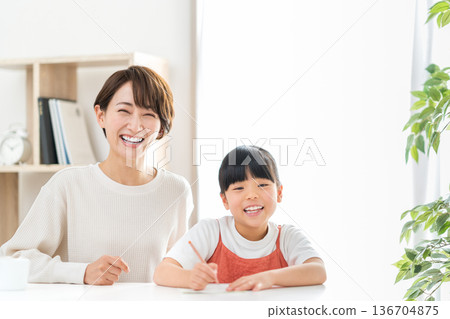 一位母親站在正在學習的小學生孩子旁邊。 136704875