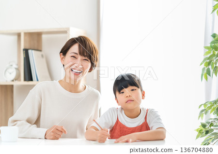 一位母親站在正在學習的小學生孩子旁邊。 136704880