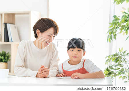 一位母親站在正在學習的小學生孩子旁邊。 136704882