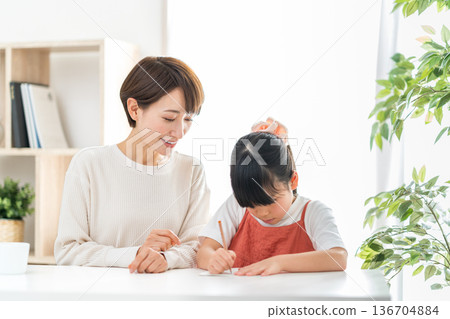 一位母親站在正在學習的小學生孩子旁邊。 136704884