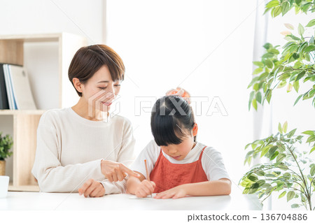 一位母親站在正在學習的小學生孩子旁邊。 136704886