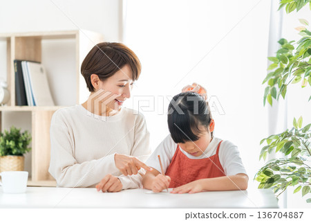 一位母親站在正在學習的小學生孩子旁邊。 136704887