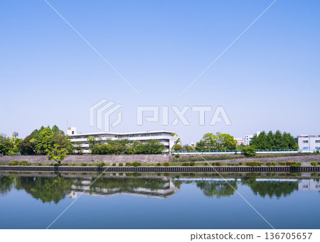 The school and fresh greenery reflected on the river surface 136705657