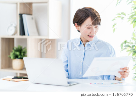 A woman working remotely in the living room. 136705770