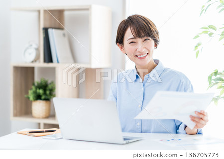 A woman working remotely in the living room. A woman working remotely in the living room. 136705773