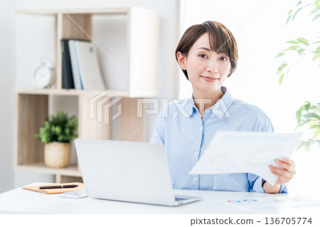 A woman working remotely in the living room. A woman working remotely in the living room. 136705774