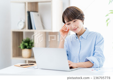 A woman working remotely in the living room. A woman working remotely in the living room. 136705778