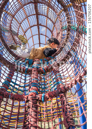 Vertical image of children playing on rope play equipment Vertical image of children playing on rope play equipment 136706207