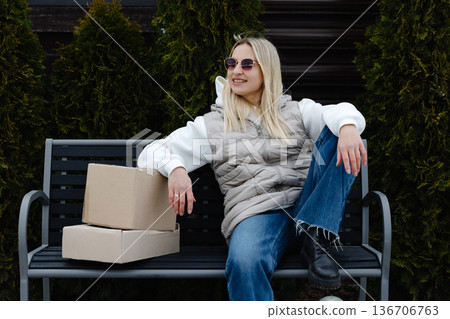 Young Woman Relaxing on Bench After Receiving Packages Young Woman Relaxing on Bench After Receiving Packages 136706763