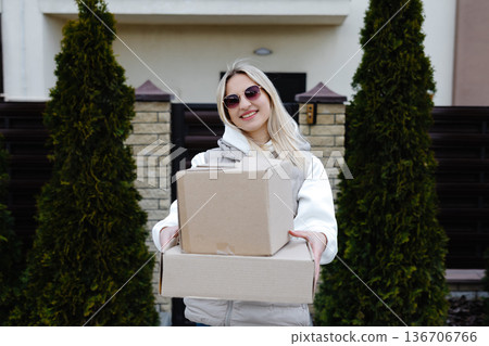 Smiling delivery woman holding a big cardboard box 136706766