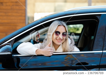 Happy blonde businesswoman gesturing thumbs up from car window 136706789