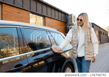Woman cleaning her car with microfiber cloth outdoors Woman cleaning her car with microfiber cloth outdoors 136706791